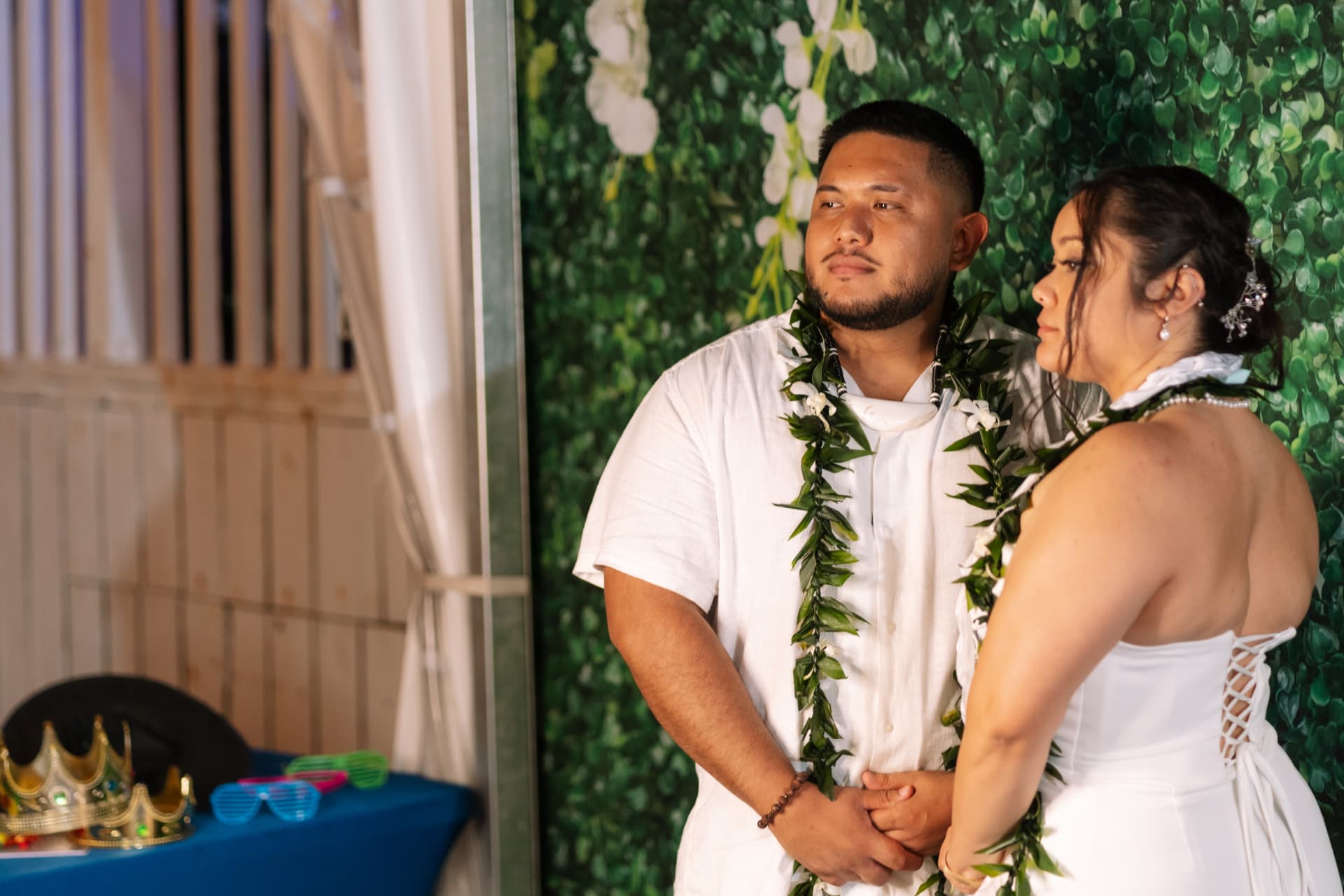 Couple in front of a greenery backdrop at the photobooth