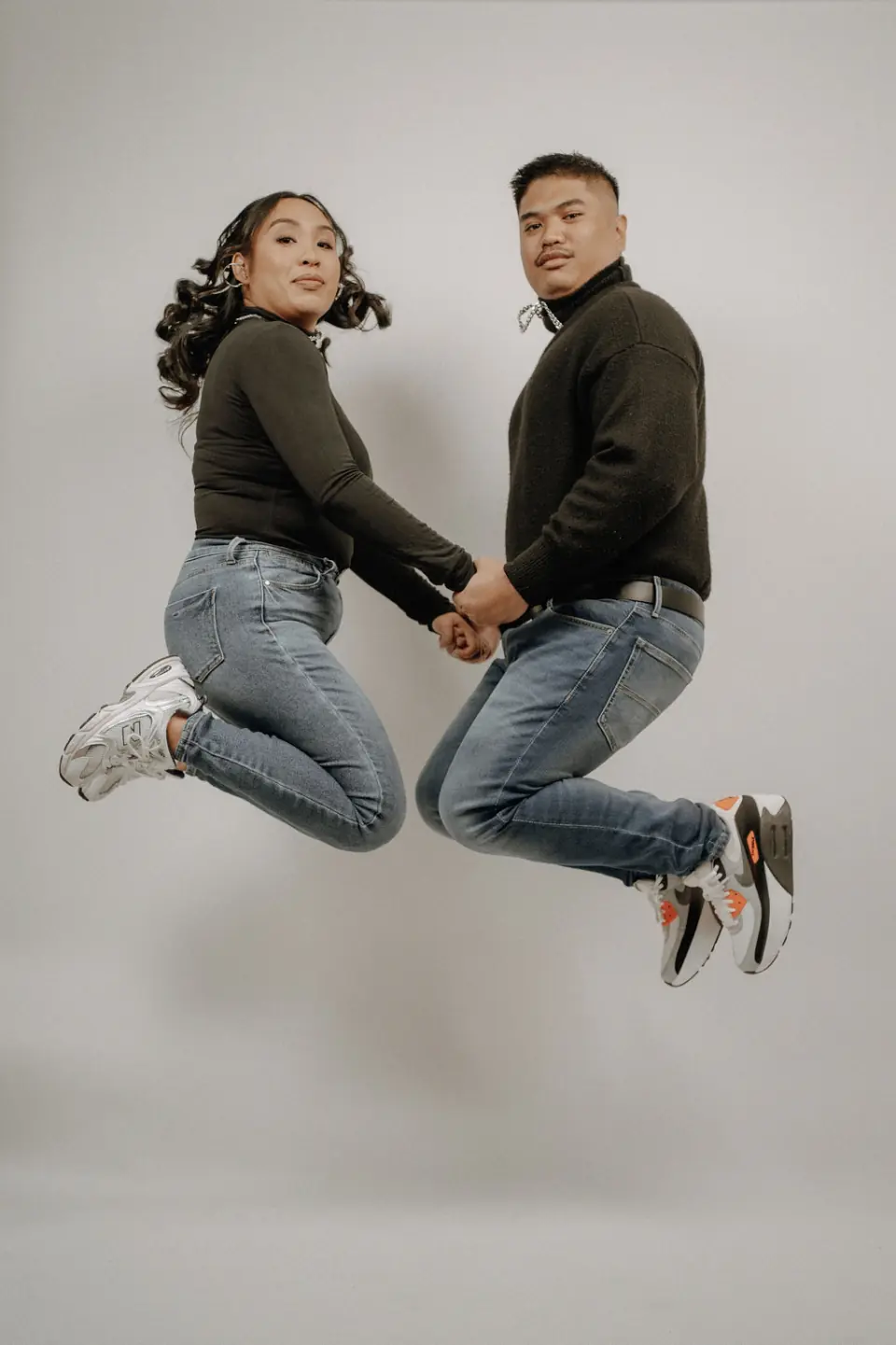 Couple jumping together against a clean studio backdrop